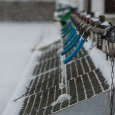 Blå vattenledningar med istappar vid en snötäckt vattenanläggning